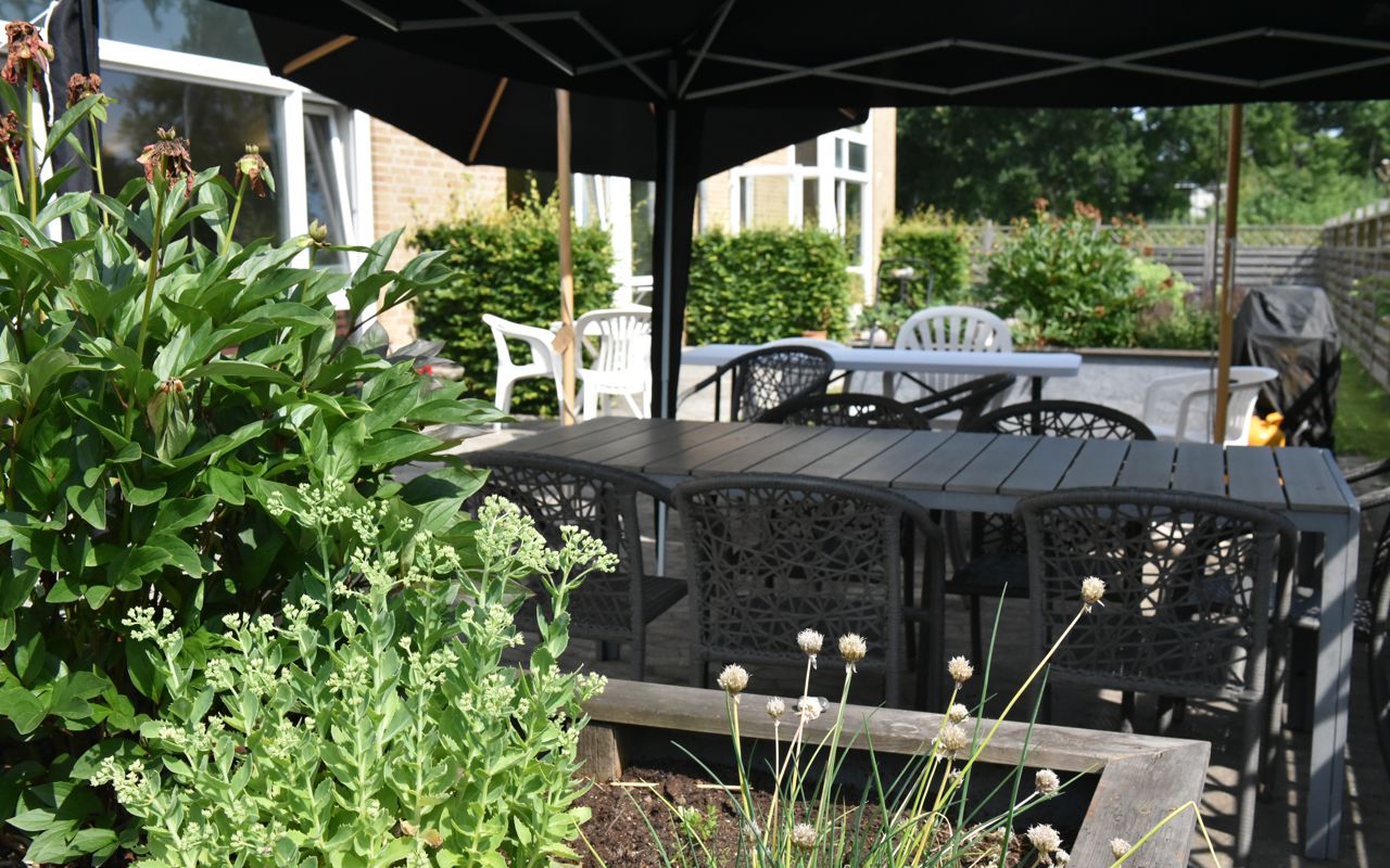 Overdækket terrasse og blomsterbed hos Kollektivhuset