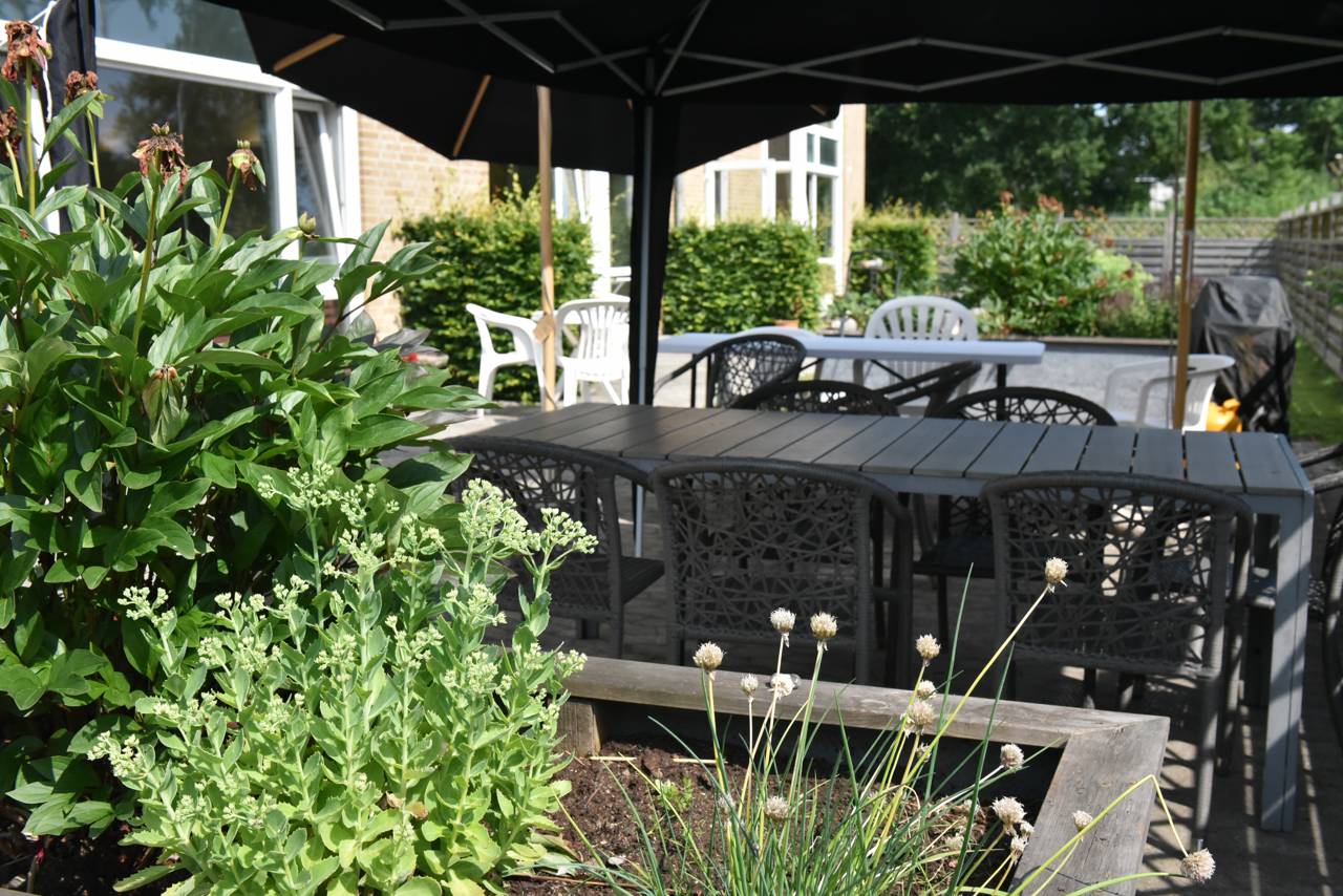 Overdækket terrasse og blomsterbed hos Kollektivhuset