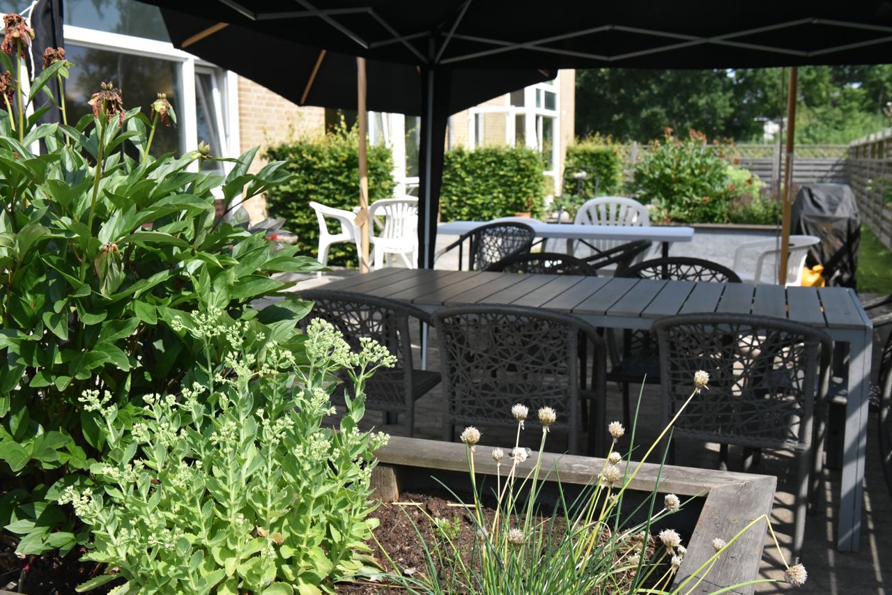 Overdækket terrasse og blomsterbed hos Kollektivhuset