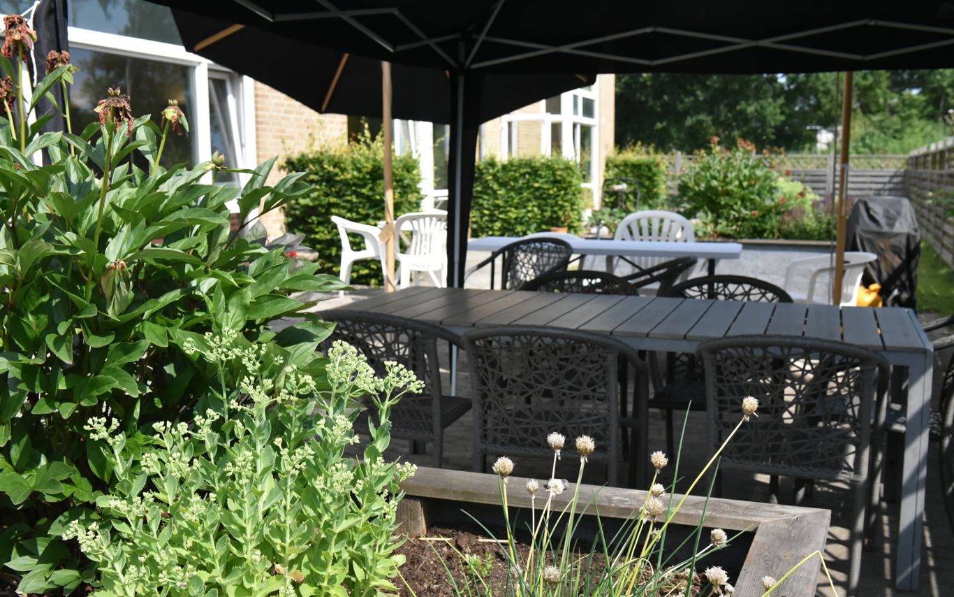 Overdækket terrasse og blomsterbed hos Kollektivhuset