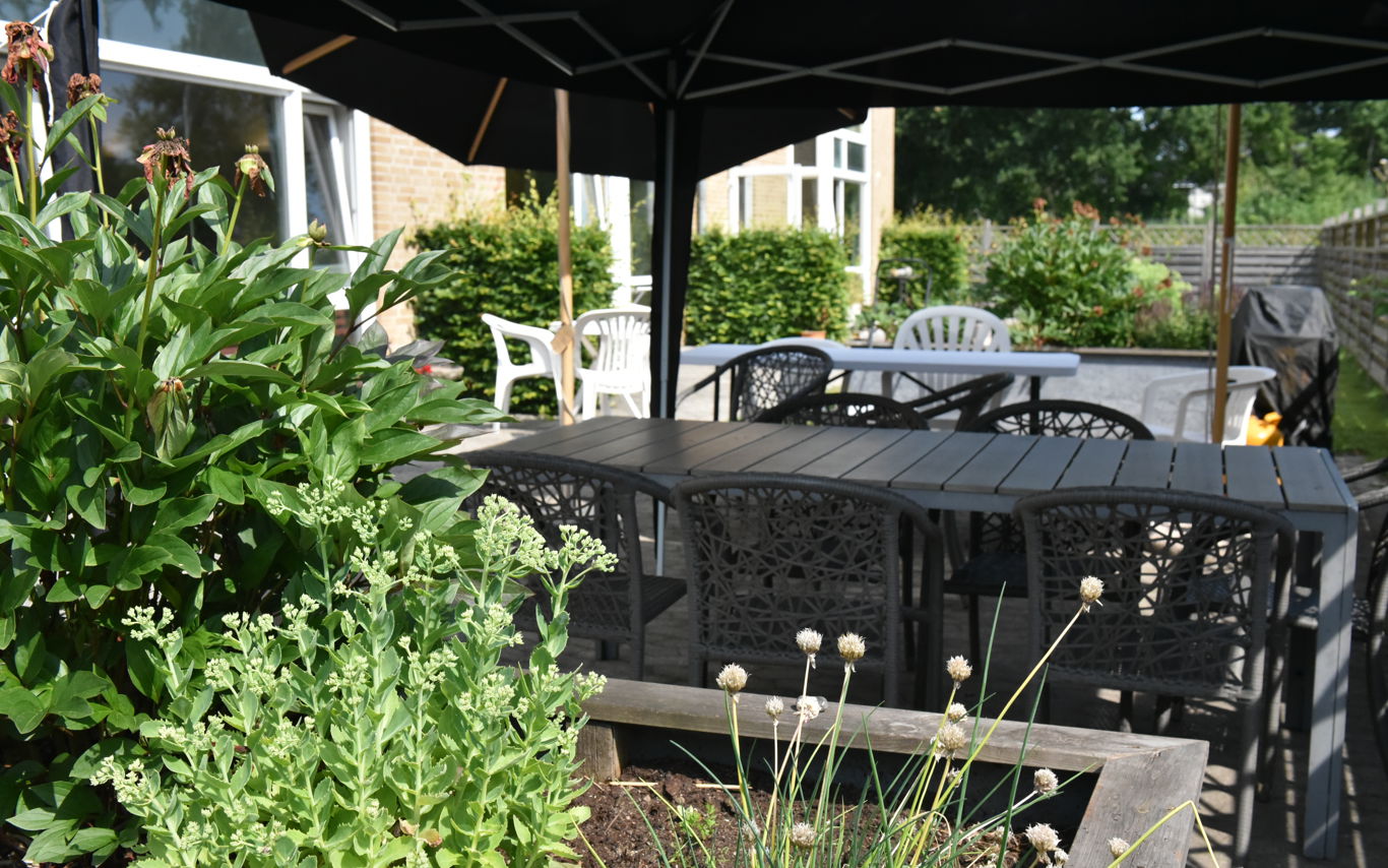 Overdækket terrasse og blomsterbed hos Kollektivhuset