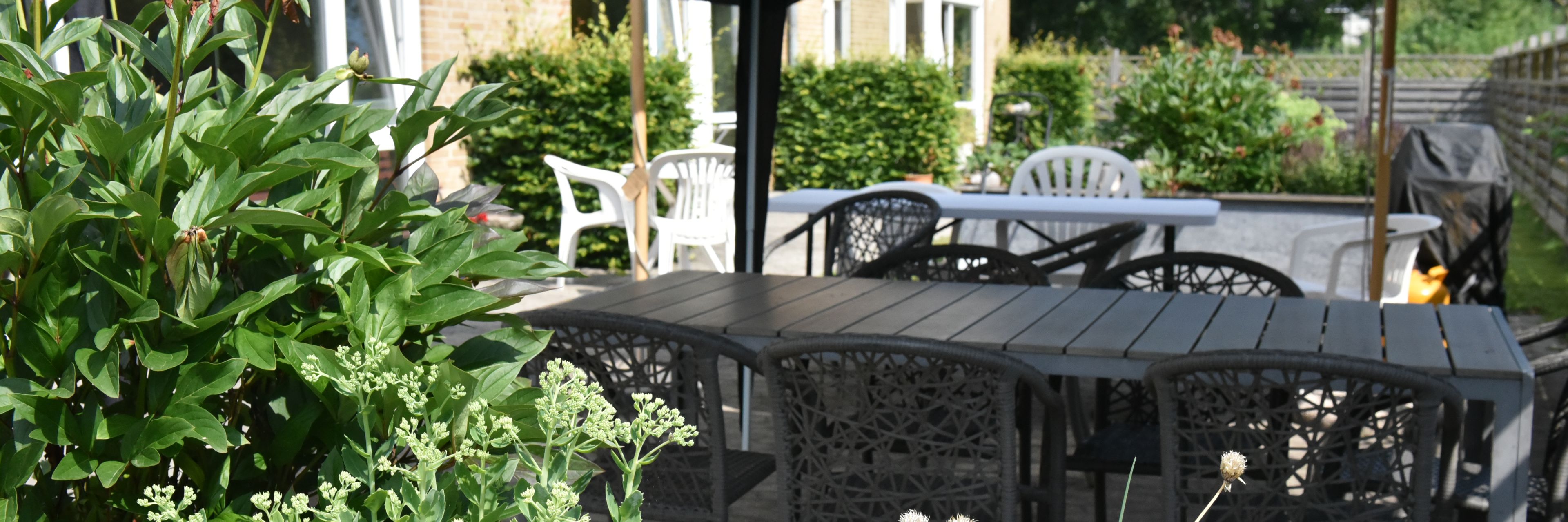 Overdækket terrasse og blomsterbed hos Kollektivhuset